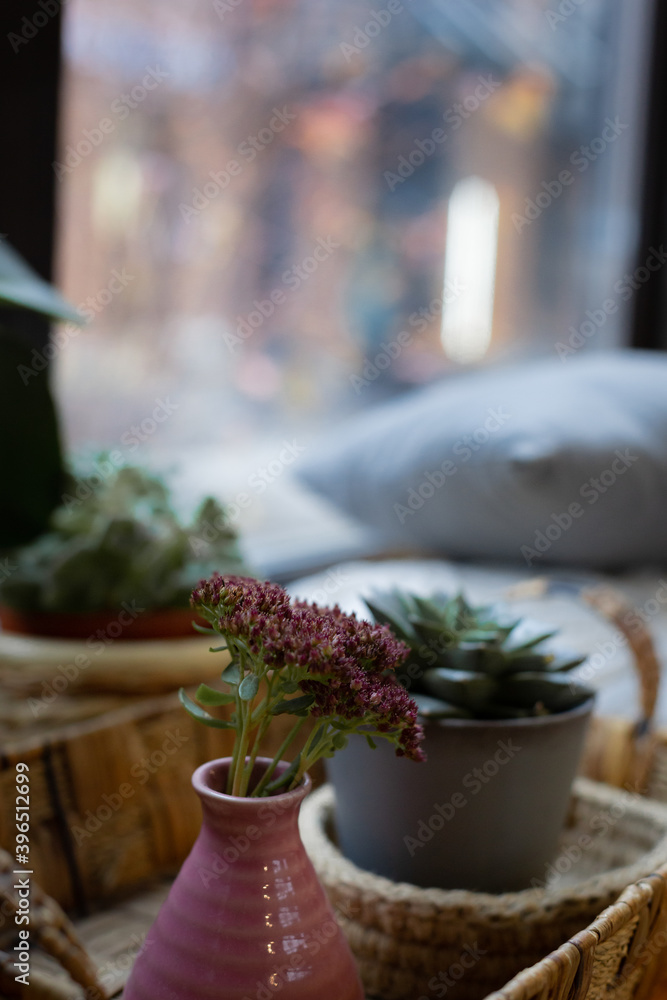 Homemade flowers in pots are on the window.