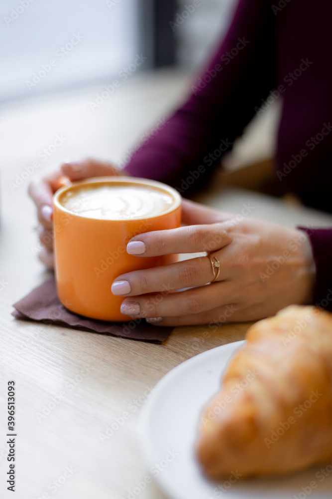 A girl has a croissant for Breakfast in a cafe