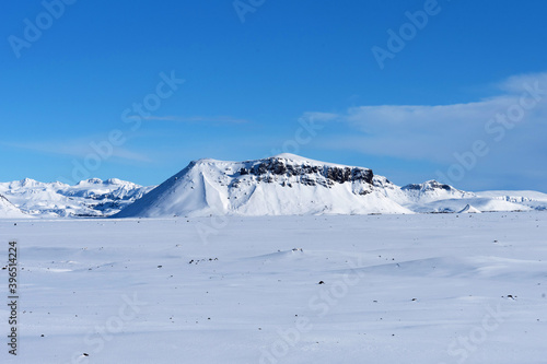 Typical Icelandic winter landscape with mountains under the snow and blue sky. Beautiful winter landscape with mountains covered snow, cold frosty weather and white field in Iceland. © Ekaterina Loginova