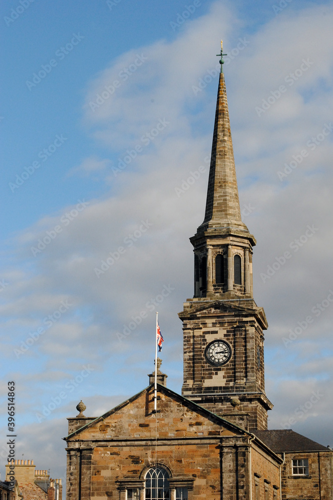 Old Rural Stone Church with Spire & Clock against Blue Sky 