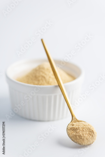 Sunflower lecithin in a bowl and spoon on a white background.