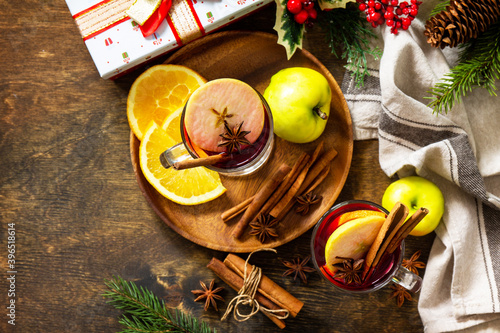 Winter Christmas hot drink with orange, apple and spices. Mulled wine in glass mug with spices on rustic table. Top view flat lay. Copy space.