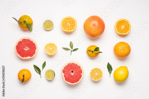 Creative neatly arranged food layout of citrus fruits and leaves on white background.  Flat lay juicy fruits concept