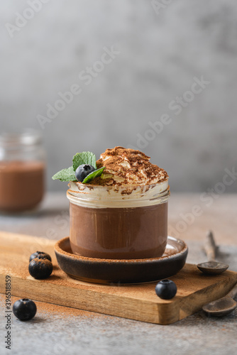 Chocolate mousse in glass jar with whipped cream and blueberries. Sweet dessert close-up view  photo