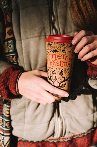 Young girl's hands with cup of coffee with "Merry Christmas"