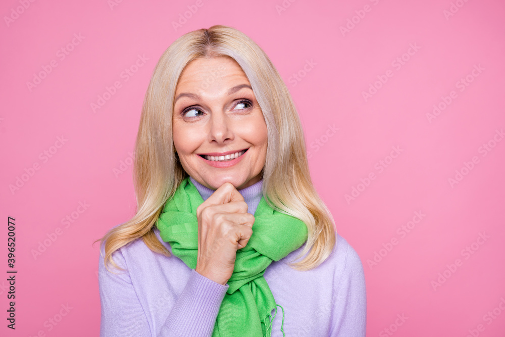 Photo portrait thoughtful curious old lady blonde hair smiling touching chin looking blank space isolated on pastel pink color background
