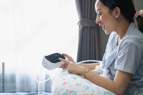 Mom use electric breast pump feeding for her baby.