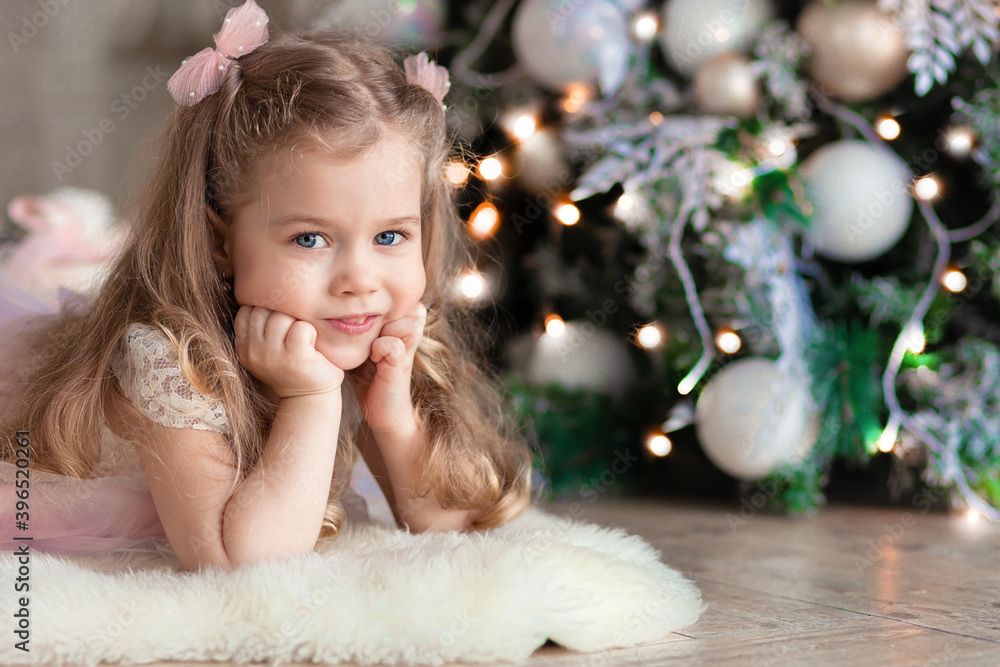happy little girl under the christmas tree. cute baby is waiting for gifts for the new year. happy child smiling on xmas eve and waiting a santa. childhood, concept of holiday, miracle