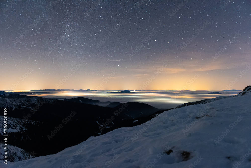 Magic starry night over the mountains and foggy valley in winter, Low Tatras National Park Slovakia