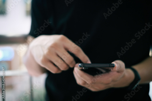 Closeup of male hand holding modern smartphone, man's hand using cellphone at night city, bokeh light, Selective focus. © BoszyArtis