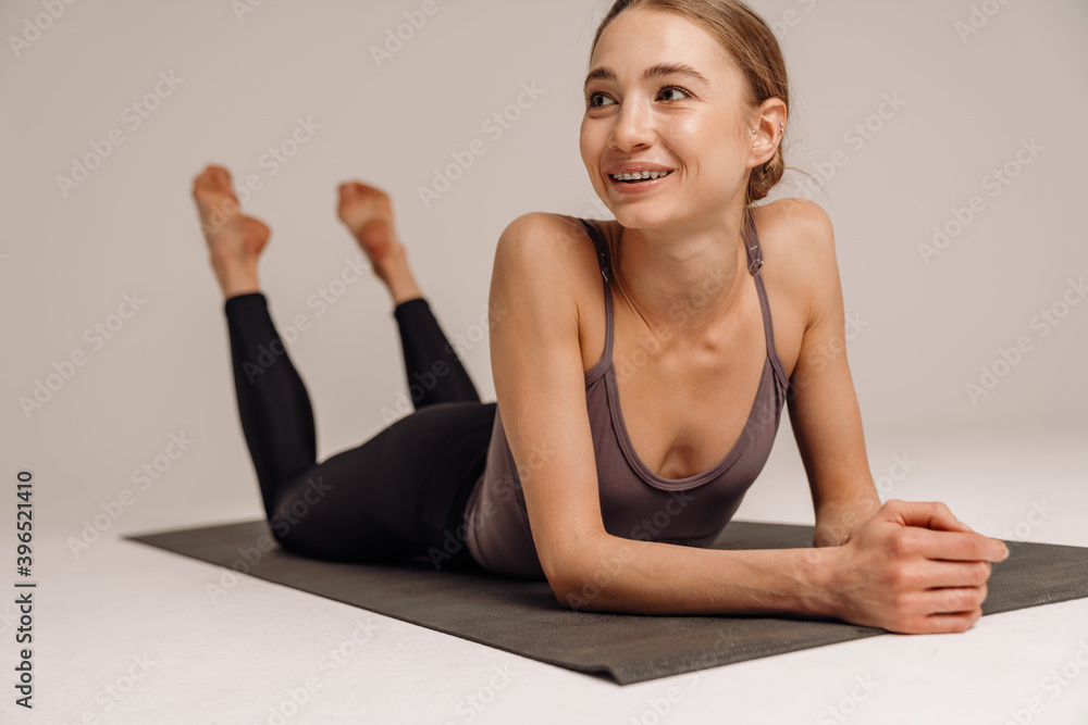 Fototapeta premium Beautiful laughing sportswoman resting while working out on mat