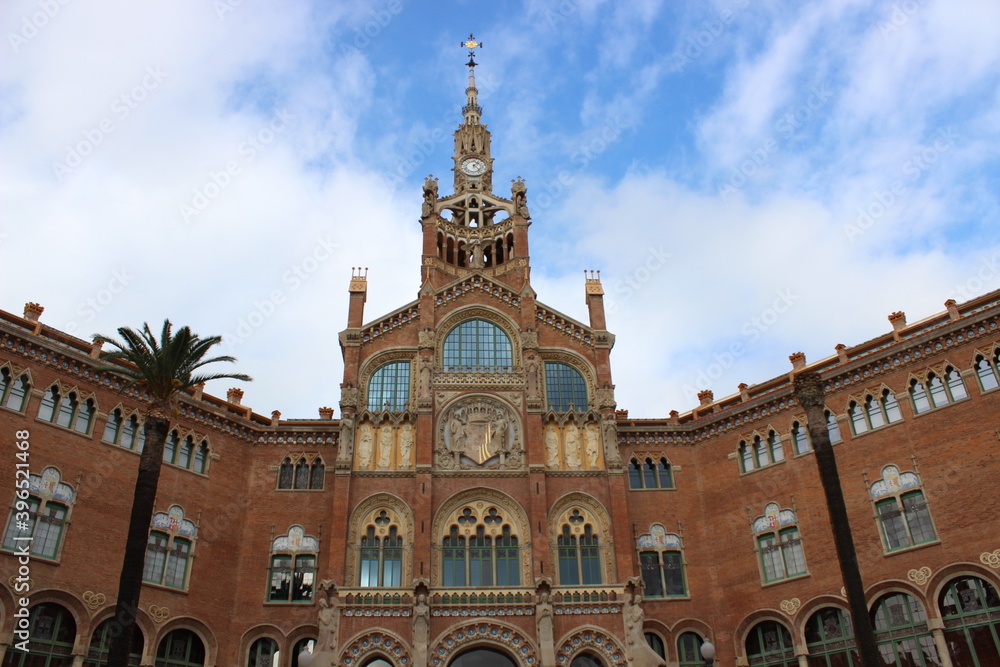 fachada del Hospital de la Santa Creu i Sant Pau en Barcelona, un edificio modernista con palmeras en su entrada
