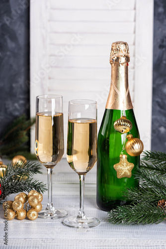 Bottle and glasses of champagne. New Year or Birthday party with a gold Christmas tree ornaments and baubles