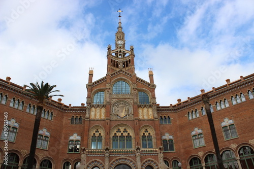 fachada del Hospital de la Santa Creu i Sant Pau en Barcelona, un edificio modernista con palmeras en su entrada 