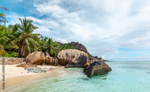 Waterfront view at beautiful tropical coast with granite boulders, tropical palms and turquoise water