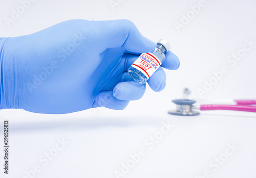 Covid 19 vaccine development test sample At the doctor wearing blue gloves, put the vial on the table and have a stethoscope Blur in the background.Vaccine of fight against coronavirus Concept.