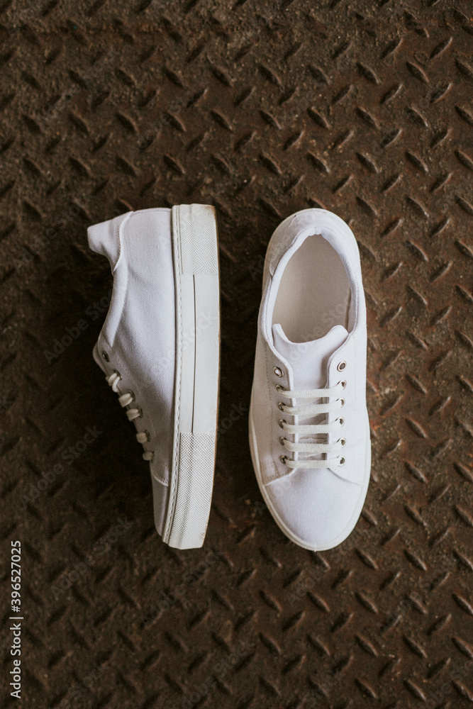 Fototapeta premium White canvas sneakers on metal texture