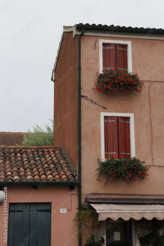 classic, small brick-colored house in a small Italian town, with balconies and flowers