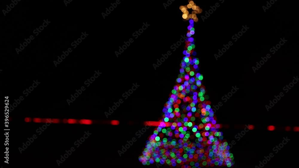 Out of focus christmas tree decorated in lights with a star at the top Out of focus christmas tree decorated in lights with a star at the top