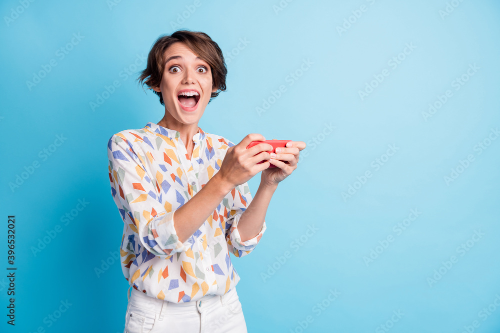 Photo of cheerful positive amazed young woman hold use phone gamer unbelievable win isolated on pastel blue color background Photo of cheerful positive amazed young woman hold use phone gamer unbelievable win isolated on pastel blue color background