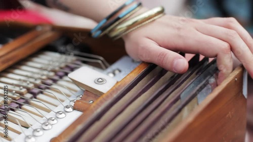 Closeup of hands of a woman with bracelets playing harmonium