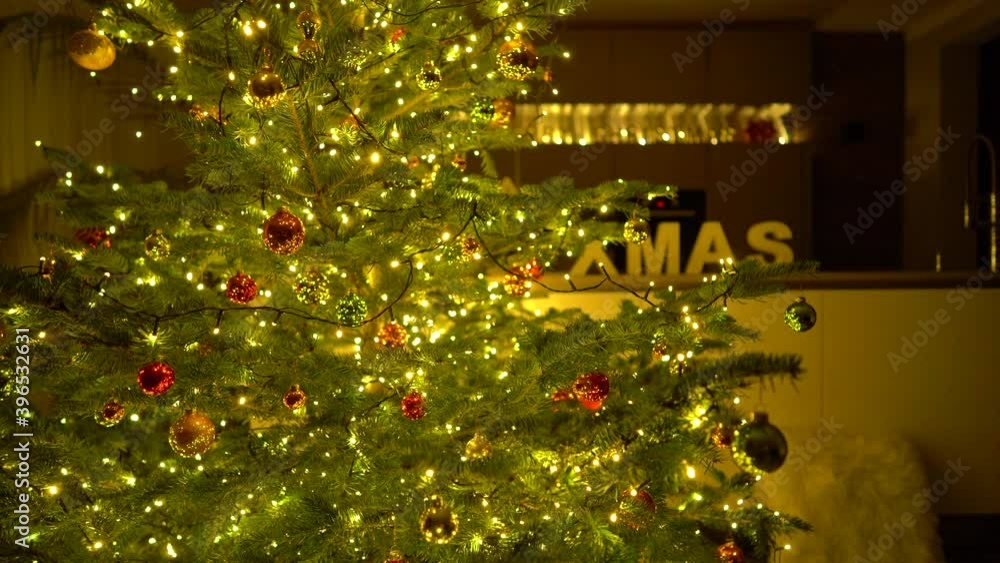Beautiful decorated and lighted christmas tree in living room, background blurred, medium dolly shot in 4k