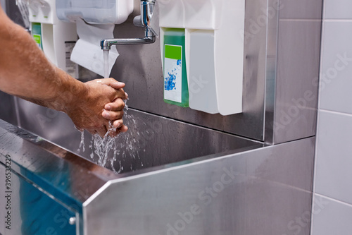 sterility, cleanliness concept. cropped male doctor washing hands after operation, keep hands clean. photo