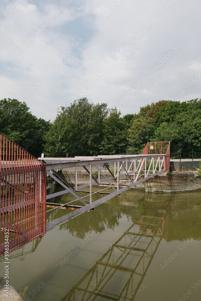 abandoned bridge without base bottom steel red over quay water river lake green with trees in the background abandoned bridge without base bottom steel red over quay water river lake green with trees in the background