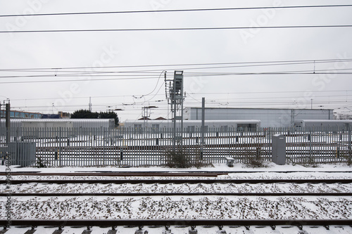 train tacks in the snow side view with cable lines telephone electric running over head winter white cloudy