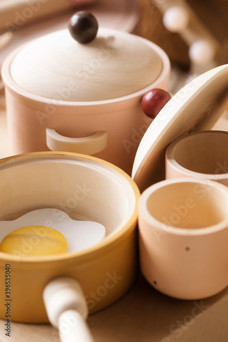 Children's tableware made of natural wood in pastel colors. Children's kitchen game, saucepan, cups, frying pan with scrambled eggs.