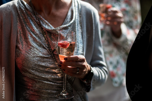 Frau in silber glitzerndem Kleid hält Glas mit Getränk wie Prosecco auf einer Party in der Hand photo