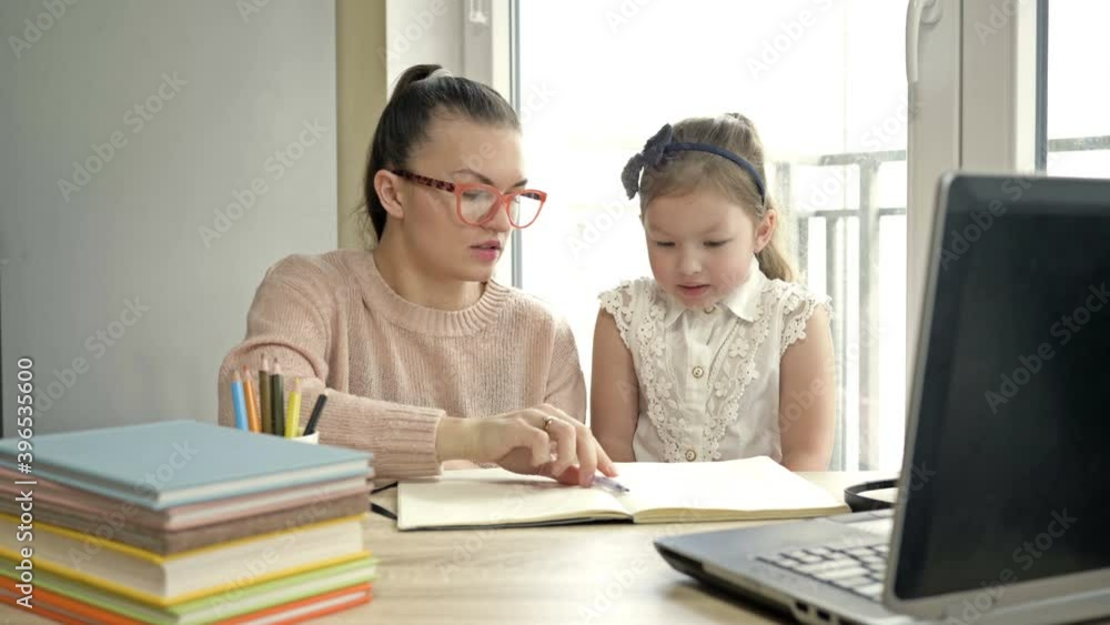 Mom helps a little elementary school student with her homework. The child is happy. Back to school. Mom helps a little elementary school student with her homework. The child is happy. Back to school.