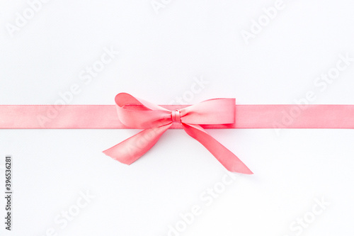Pink ribbon with bow isolated on white. Top view, copy space