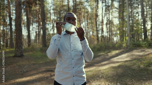 Portrait of African American business man in mask, He took off his mask and breathes freely in the forest.