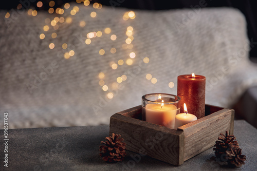 Candles in the wooden box isolated on grey white background. Garland lights. The concept of home atmosphere and comfort, holidays, romantic date, winter, home comfort, indoors, Christmas or New Year.