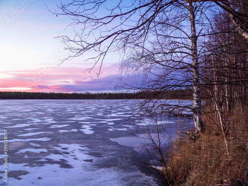 Evening winter frosty landscape with a frozen lake.