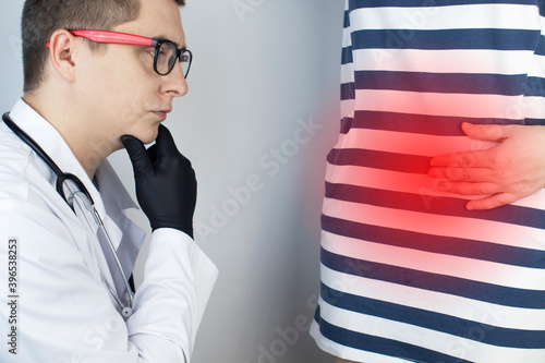 A woman holds on to his stomach. Pain in the abdominal cavity. The concept of diseases of the stomach and digestive system. The doctor will palpate to find out the source of the pain photo