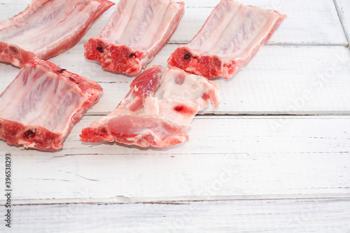 Bones, protein, uncooked pork ribs on a white wooden background.