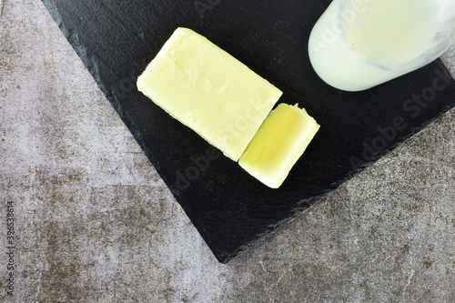 Close up, block of butter and bottle of milk on slate table. 