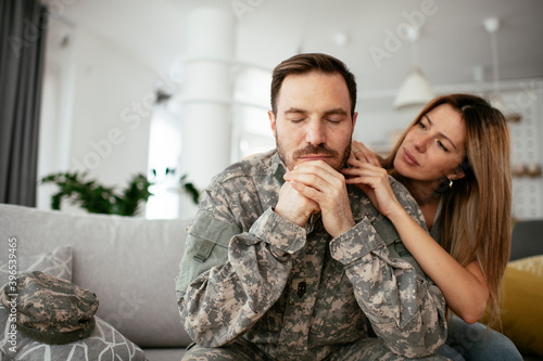 Depressed soldier sitting on sofa in living room. Young marine having PTSD
