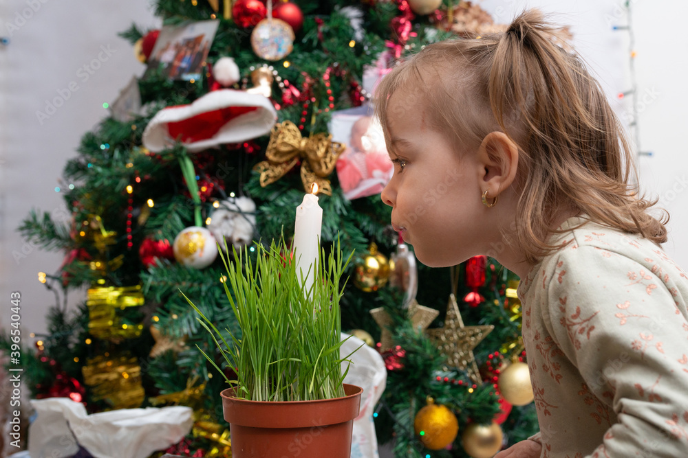 Little girl playing next to Christmas tree, dancing, singing and making a secret sweet  wishes to send to Santa
