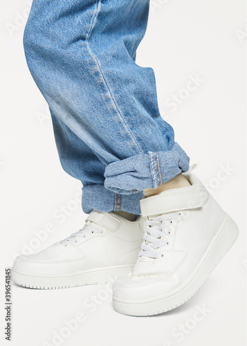 Child with jeans white sneakers studio shot