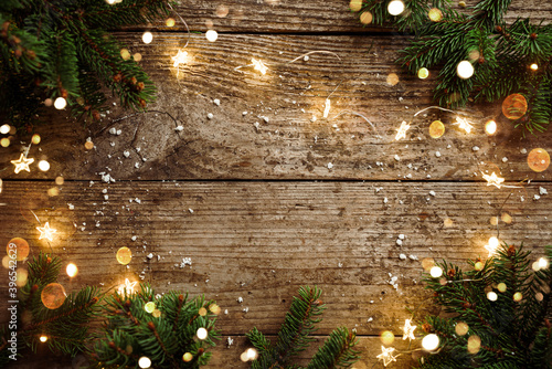 Merry Christmas frame made of Christmas decorations, fir branches, spruce, lights garland, snowflakes on wooden background. Xmas and New Year holiday, bokeh, light. Flat lay, top view
