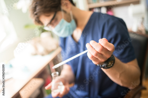 Young scientist holding a test tube in the lab wearing protective face mask and glasses.