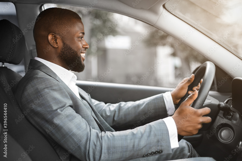 Joyful black businessman driving home after working day Joyful black businessman driving home after working day