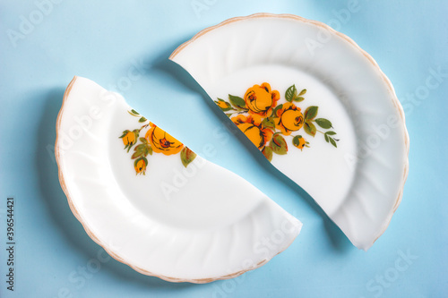Obraz na plátně Broken in two halves a plate with a pattern in flowers on a blue background
