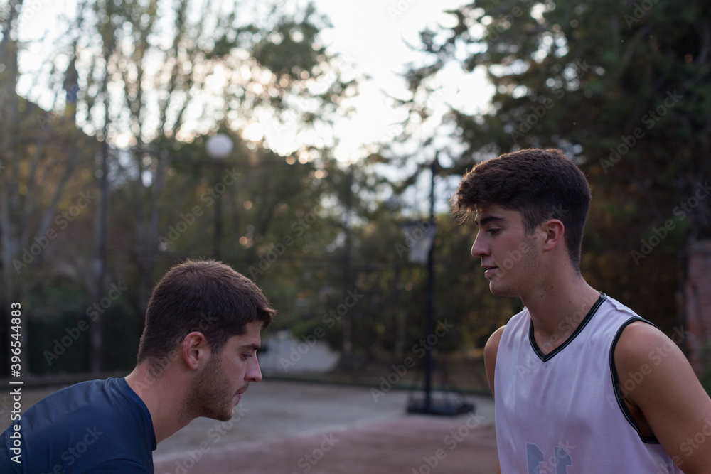 Two teenage brothers playing basketball at sunset Two teenage brothers playing basketball at sunset