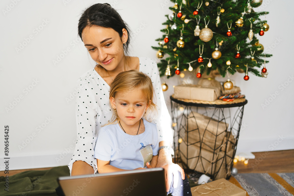 Attractive young woman with cute little daughter chatting online, congratulating family or friends with digital tablet..Video chat with parents and grandparents on Christmas Eve. Attractive young woman with cute little daughter chatting online, congratulating family or friends with digital tablet..Video chat with parents and grandparents on Christmas Eve.