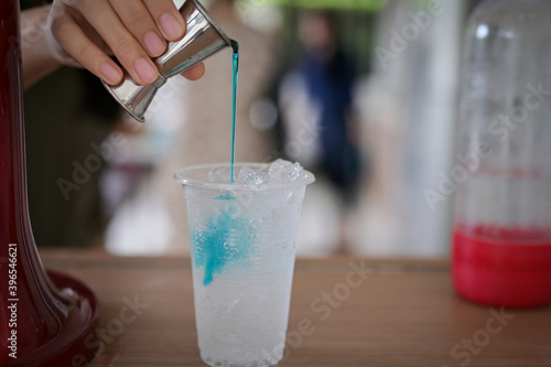 blue cream soda cocktail Brew water by women with ice in plastic glass on the wooden tablue