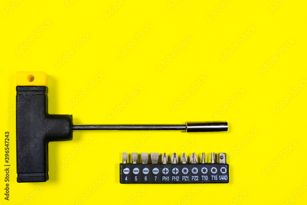 A set of screwdriver nozzles and a screwdriver on a yellow background with space for copyspace text. Tools for construction and repair shop A set of screwdriver nozzles and a screwdriver on a yellow background with space for copyspace text. Tools for construction and repair shop